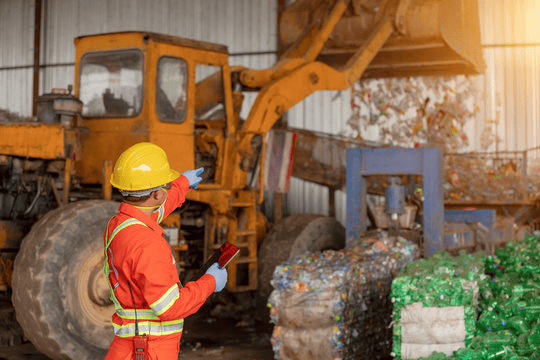 Worker in safety gear overseeing plastic recyclingโsupporting sustainable and eco-friendly packaging solutions
